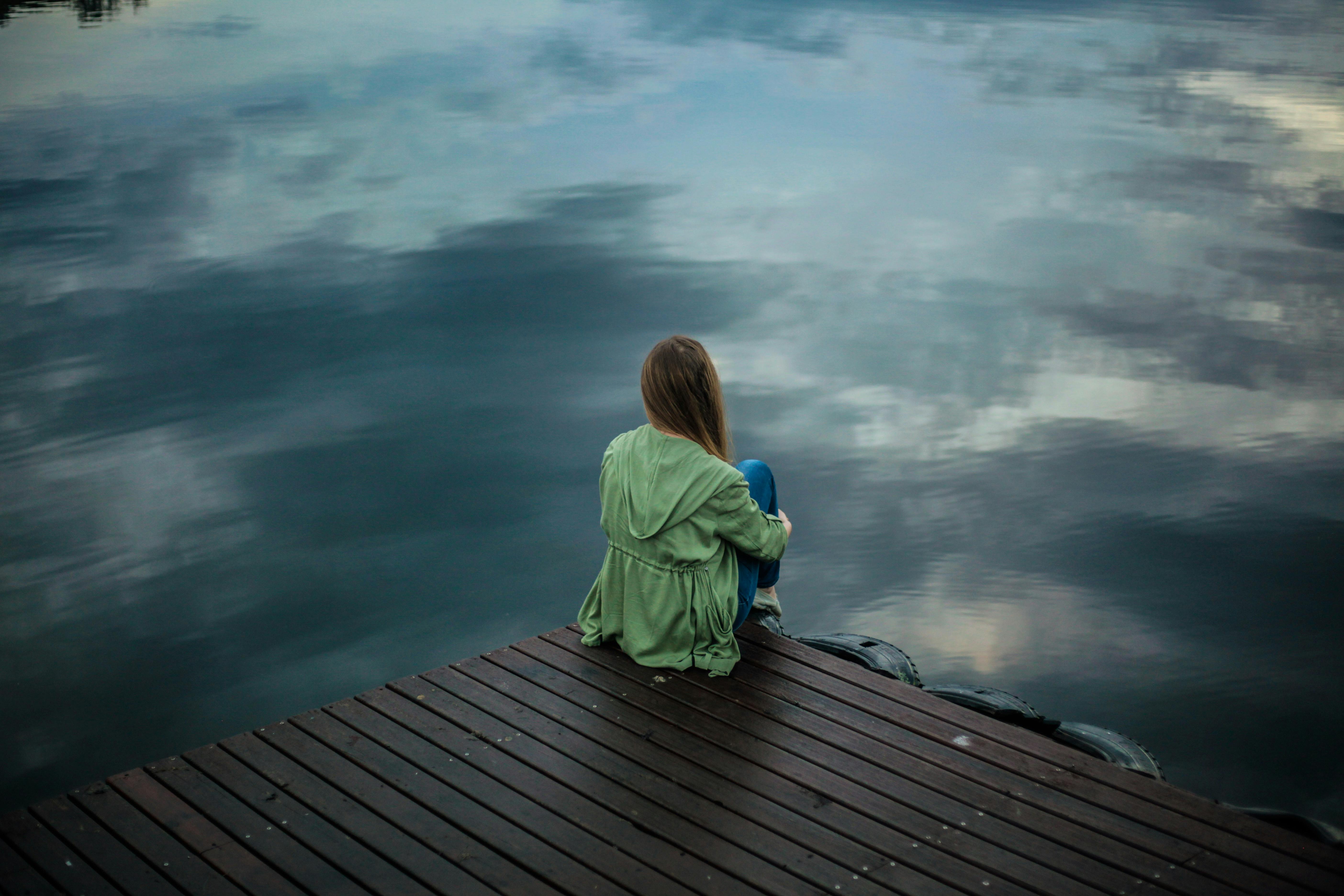 Sad woman sitting alone on the sea shore