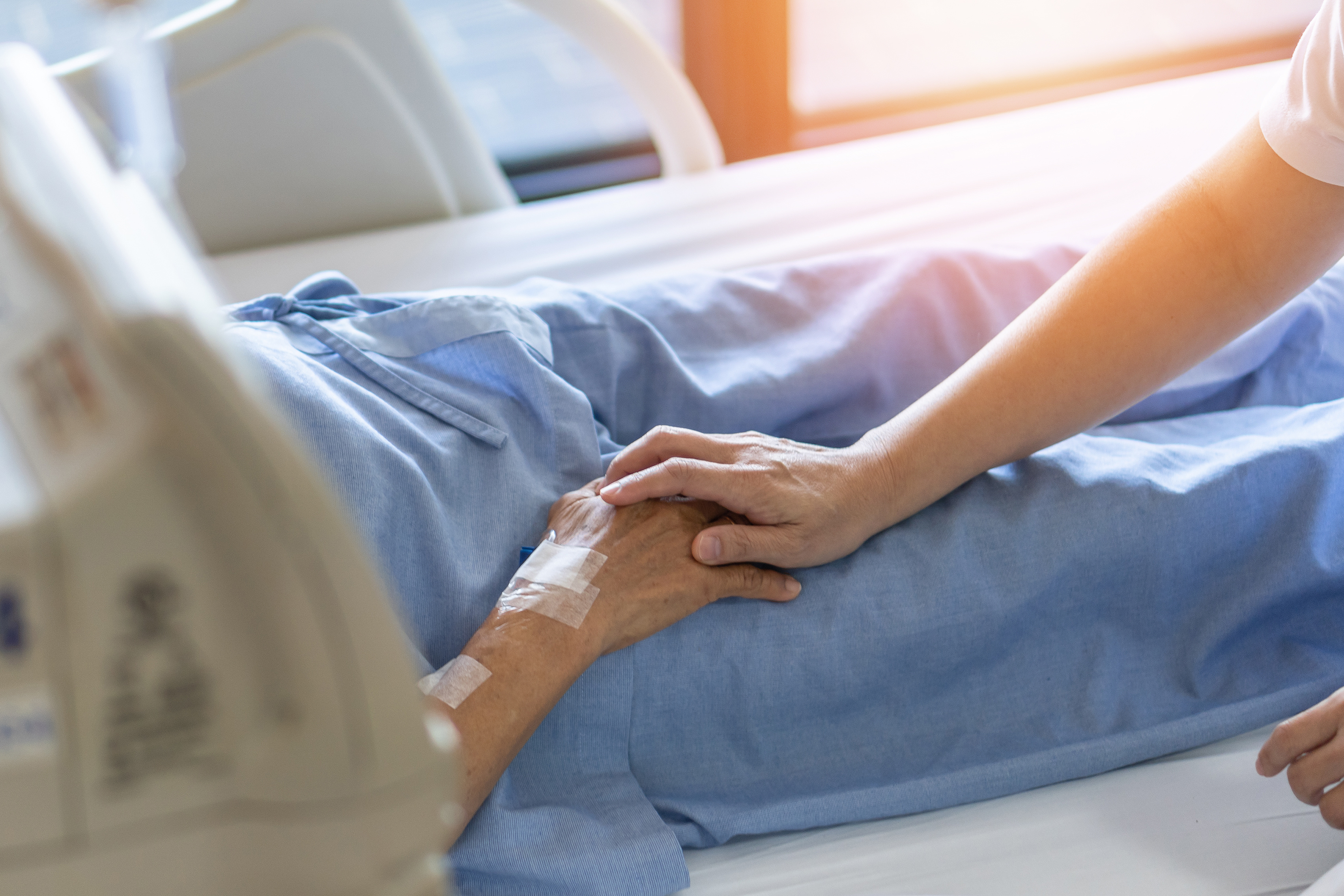 Nurse holding an the hand of an old patient